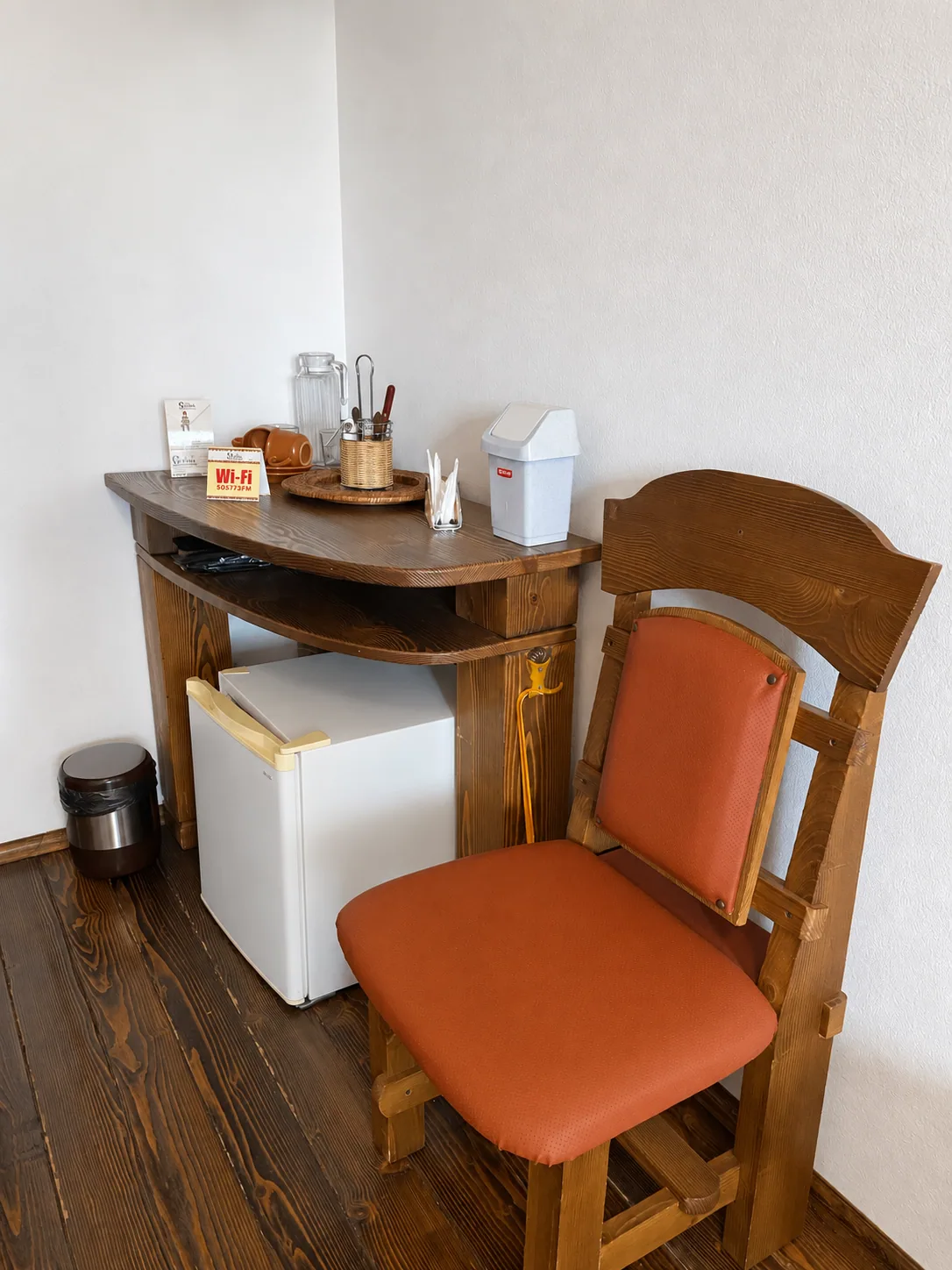 Table with a mini-fridge, glassware and a chair in the triple room