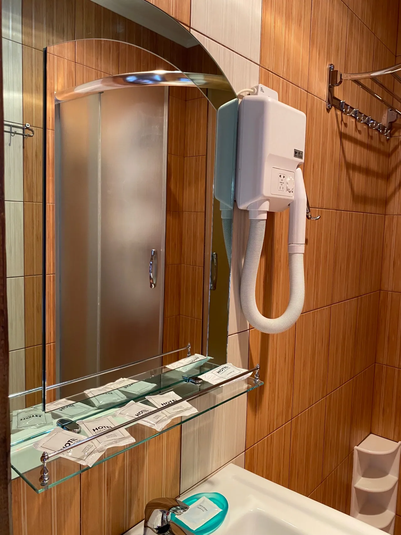 Bathroom with a washbasin, a shelf of toiletries and a wall-mounted hairdryer