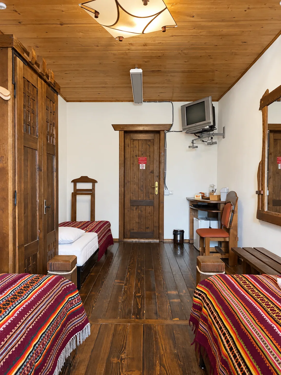 Triple room viewed from the entrance door: beds, TV and wardrobe
