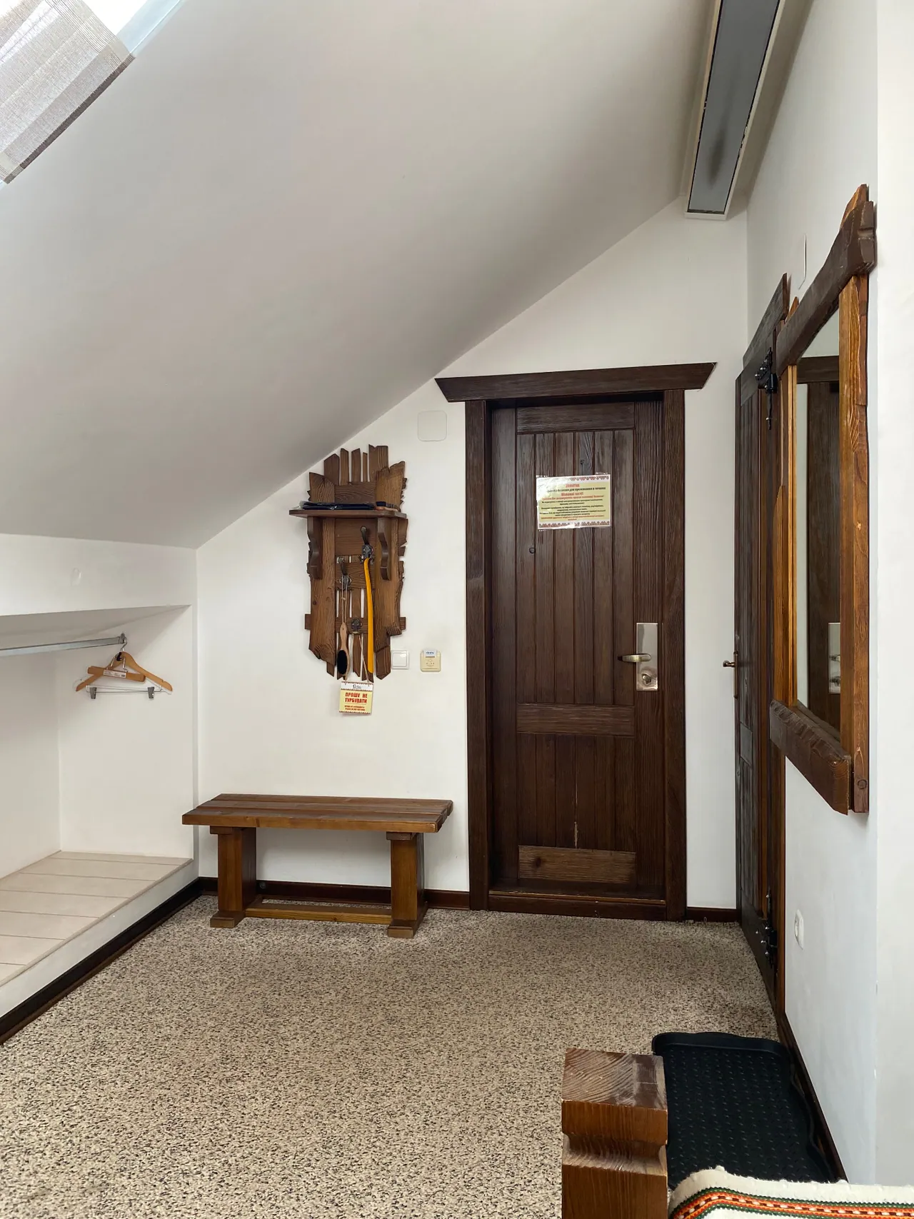 Entrance area of the attic room with a coat rack, bench and wooden door