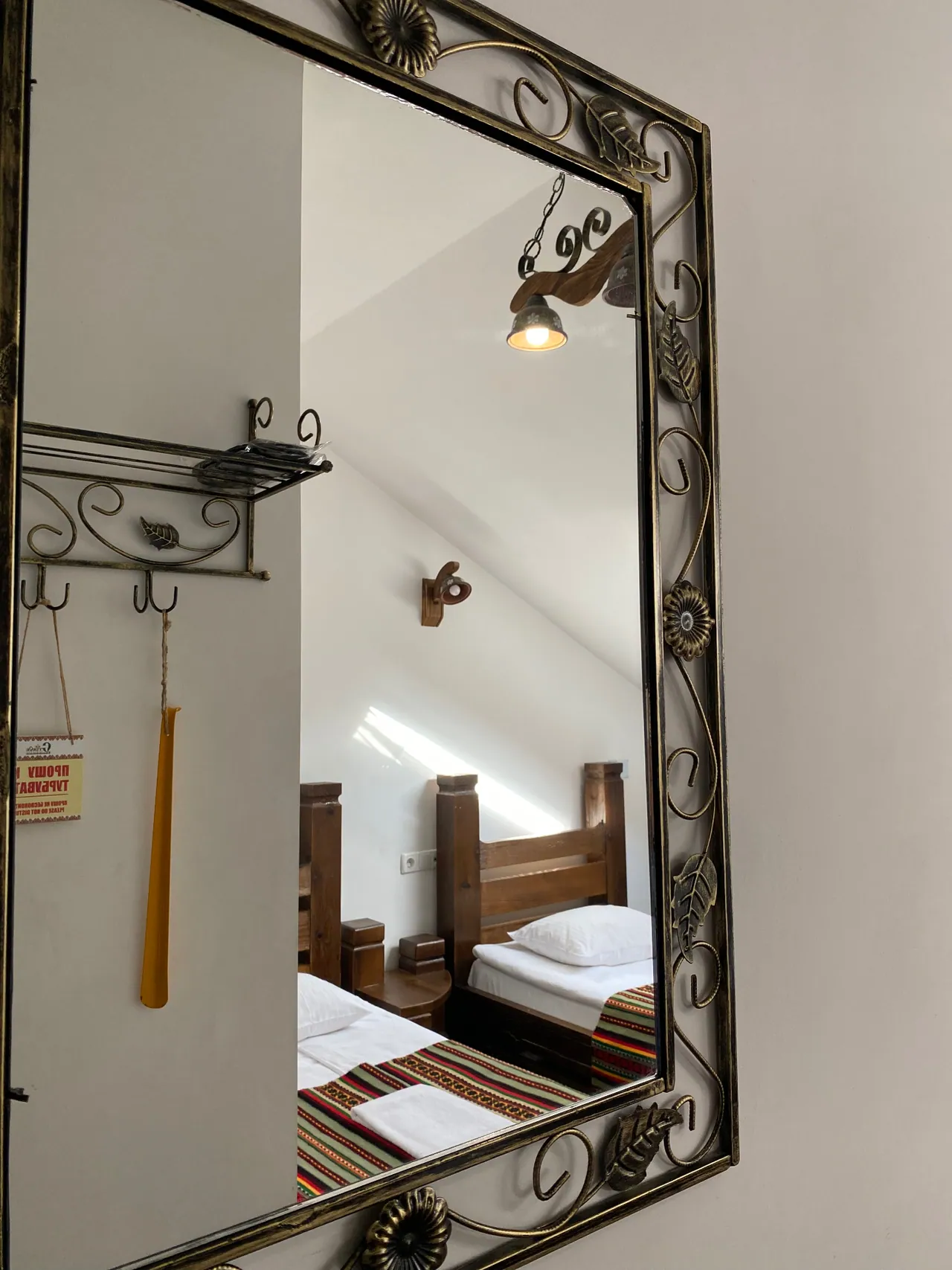 Mirror in a wrought-iron frame and hooks in the attic room