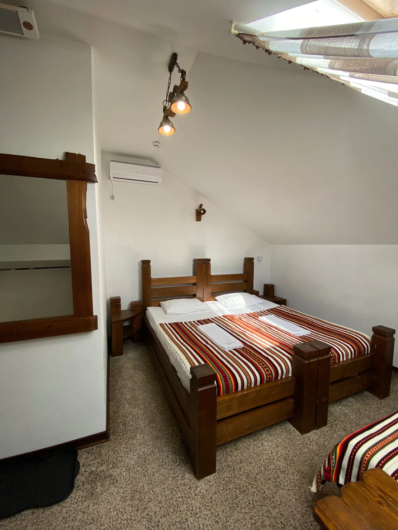 Attic room with air conditioning and a bed with a Bukovynian woven throw